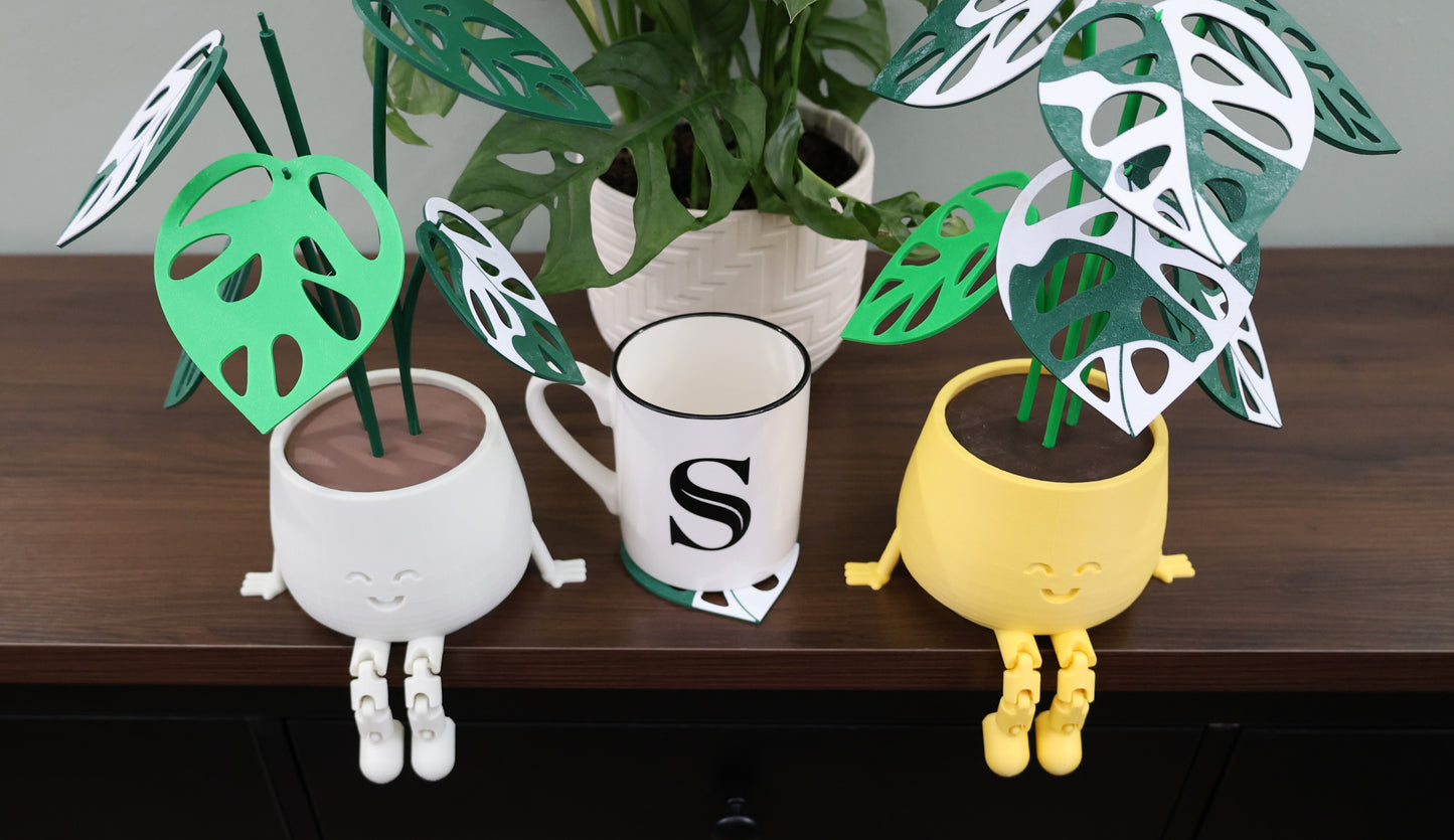 Decorative plant holders with green leaves on a wooden surface.