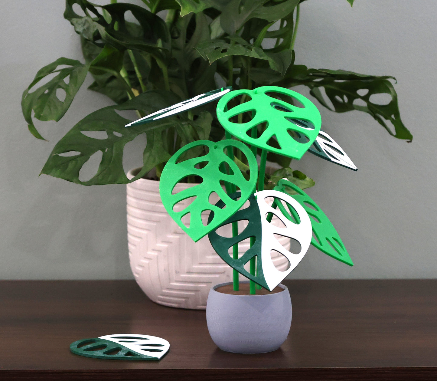 Smooth grey 3d printed plant with decorative leaf coasters on a wooden surface