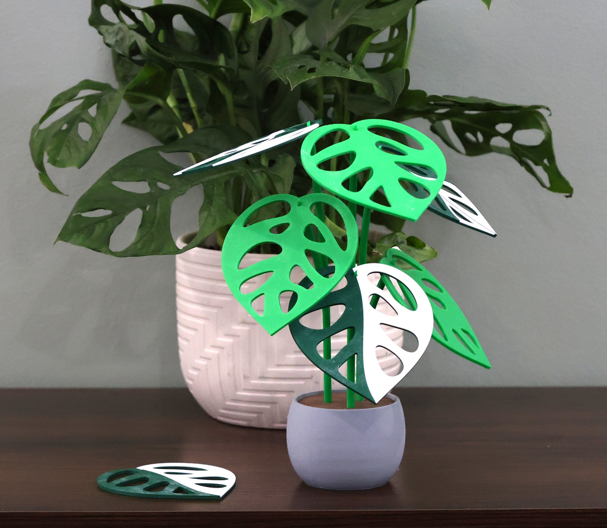 Smooth grey 3d printed plant with decorative leaf coasters on a wooden surface