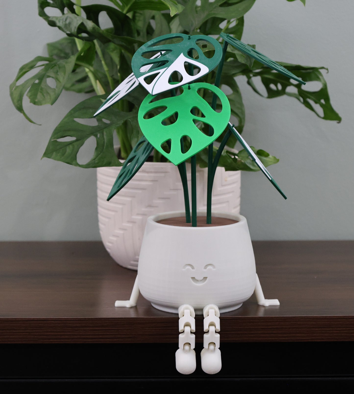 White plant stand with green leaf design on a wooden surface