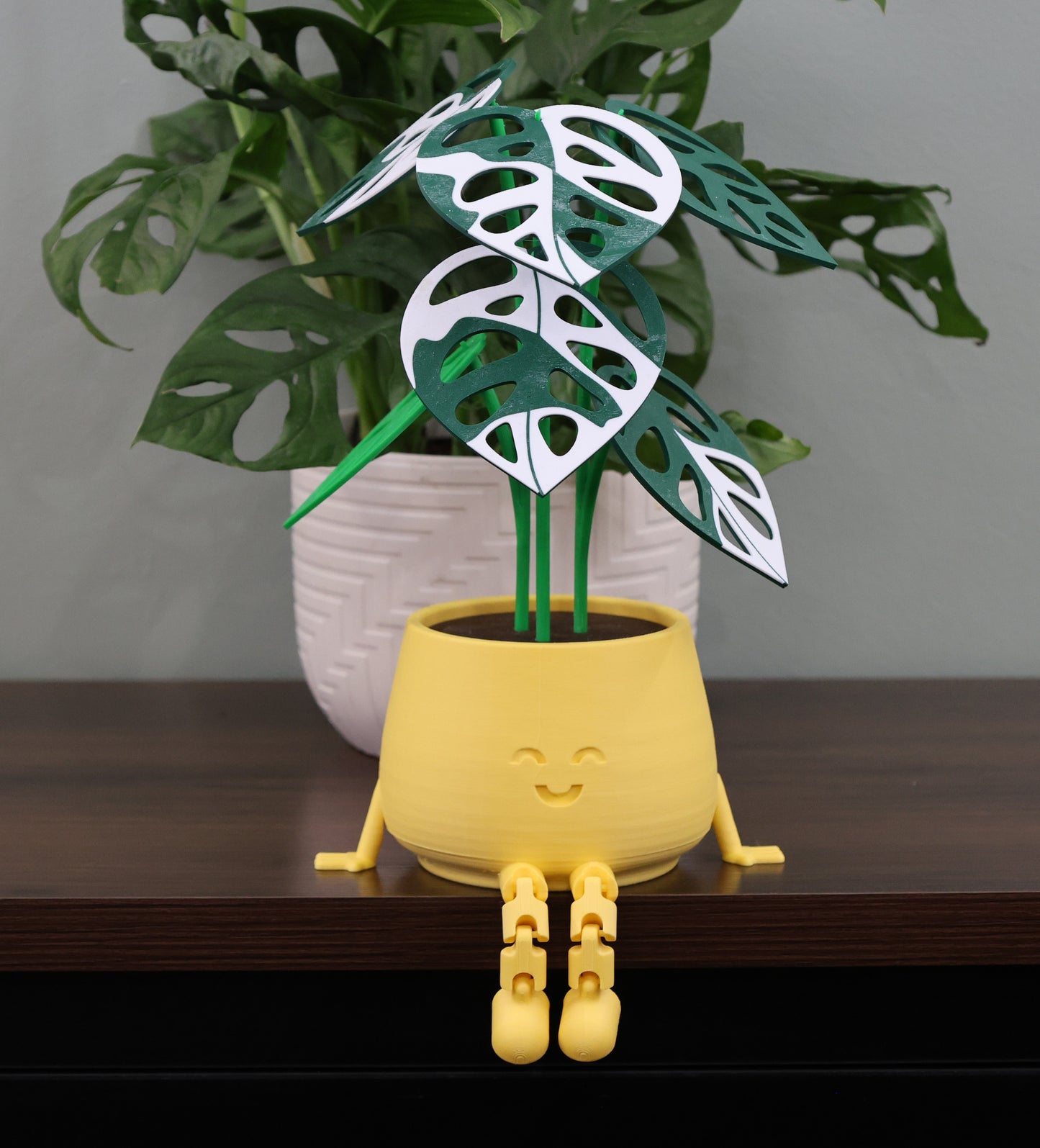 Yellow plant pot with cartoon face and leaf design on a wooden surface