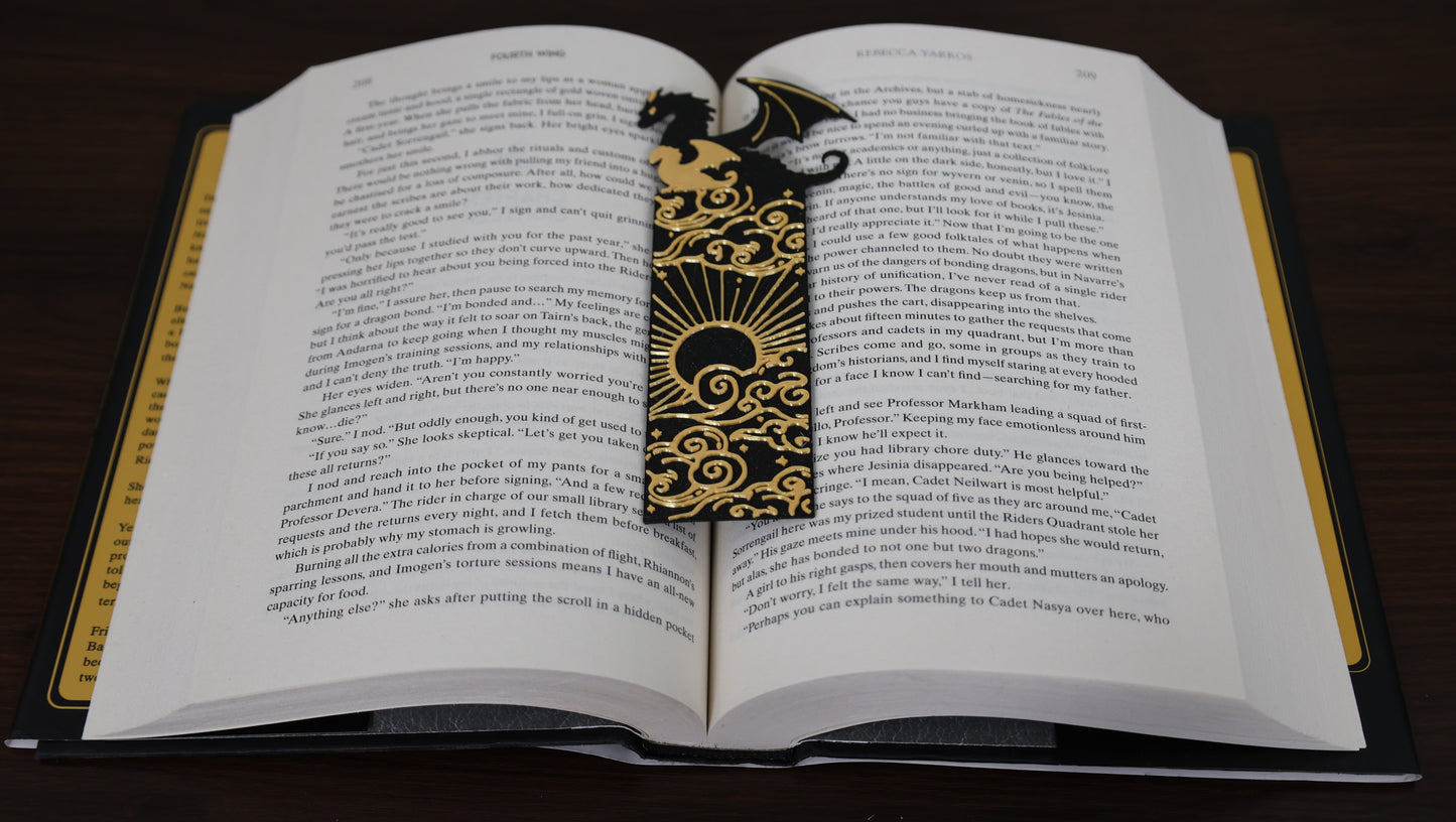 Open book with a decorative bookmark featuring a dragon design on a dark surface.