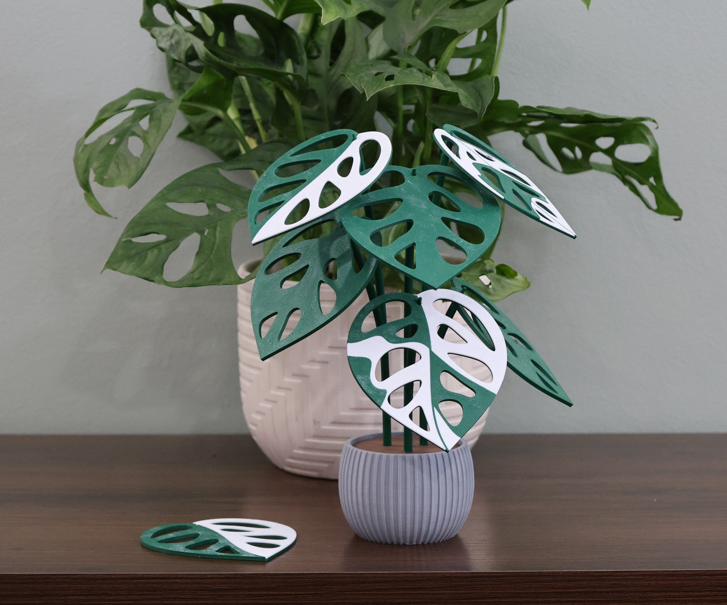 Textured grey 3d printed plant with decorative leaf coasters on a wooden surface